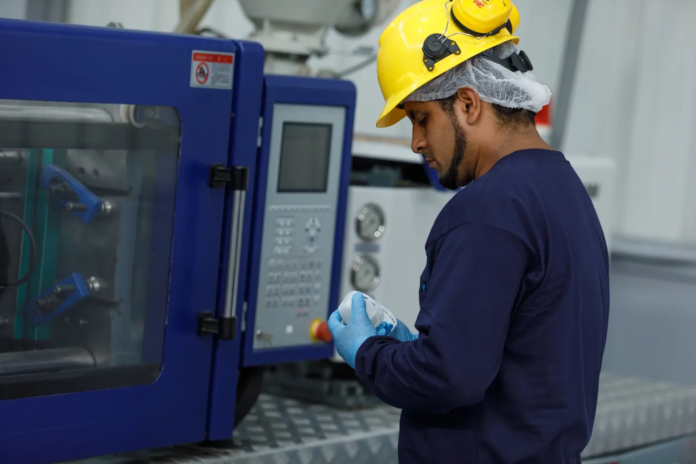 Operario de Tescom en máquina de inyección